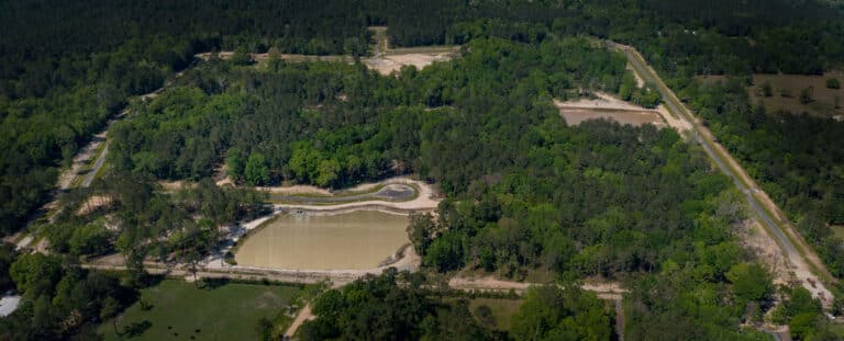Panoramic aerial view of Wingfield Estates master-planned community showing large wooded lots, new roads, and the central community pond in Covington, LA